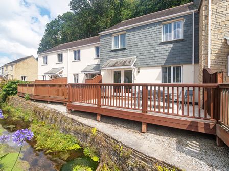 A row of houses with wooden decks overlooking a small waterway at Heron's Reach in Falmouth