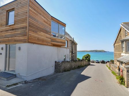 A house by the ocean and road with parked cars at The Lookout in Polzeath