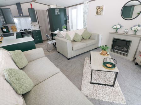 A living room with a fireplace and coffee table at Oyster Lodge in Little Haven