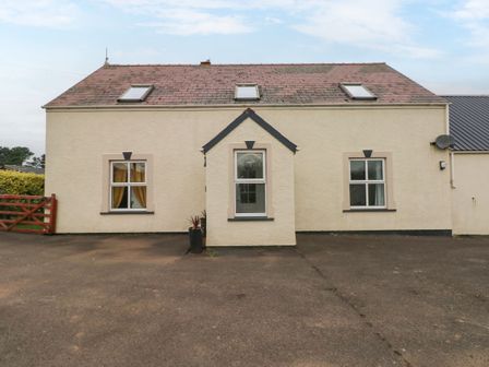 A beige house with three windows and three skylights on a paved area at Ocean House in Broad Haven