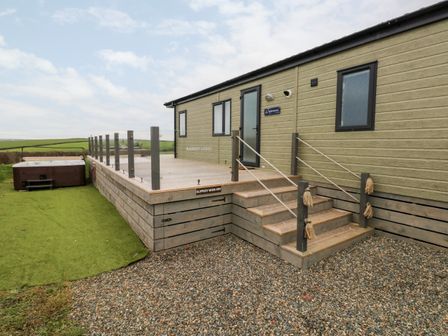 An outdoor wooden deck with stairs and rope railings attached to a single-story building with three windows and a door at Ramsey in Broad Haven