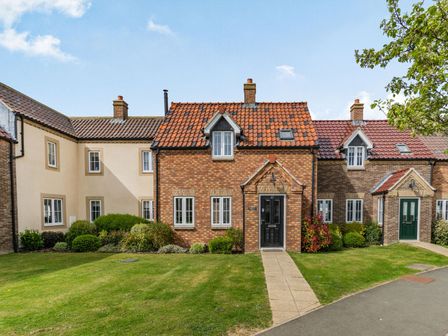 A row of brick and plaster houses with tiled roofs and front gardens at Lantern House in Filey
