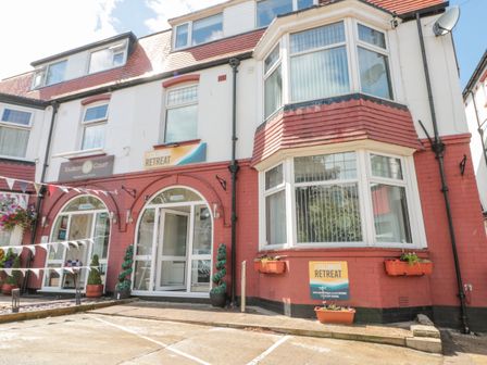 The front of a red and white building with arched glass doors and windows with flower pots and signs for Columbus Retreat in Scarborough