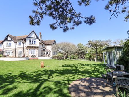 A large house with a lawn garden and wooden benches with outdoor furniture at The Seaside Inn in Beer