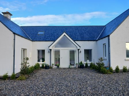 Front view of a modern house with a gravel driveway and potted plants at Lakeview Retreat in Lackaroe near Portroe County Tipperary