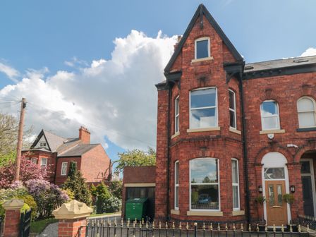 A red brick semi detached house with a bay window and a wooden front door surrounded by a black metal fence at Wellington House in Bridlington
