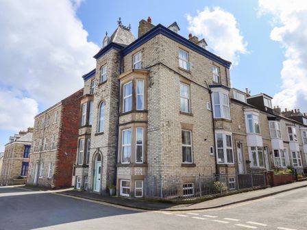 A corner view of a multi story brick residential building on a street with adjacent houses at White Horses in Whitby