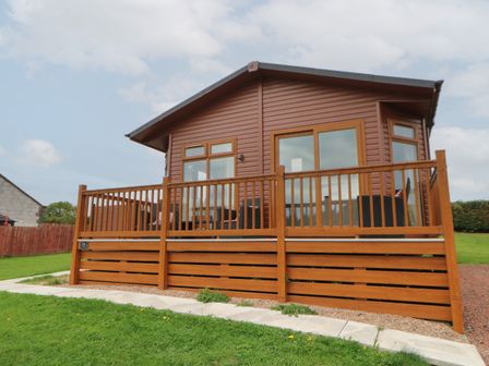A wooden cabin with large windows and a wooden deck in a grassy area at Mildred's Lodge in Felton