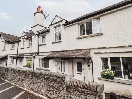A row of white terraced houses with a stone wall and wooden doors at 6 Calgarth View in Windermere