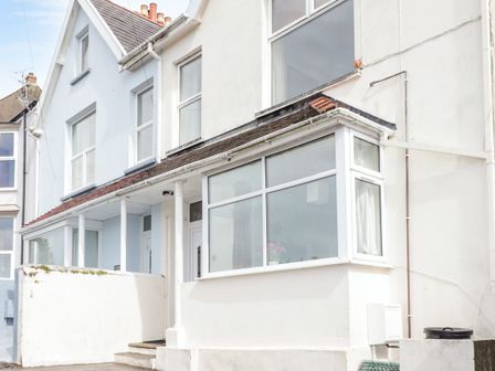A row of attached houses with large windows and front steps at Gwylan Apartment in Tenby