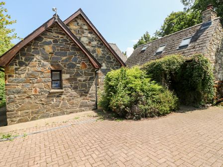An exterior view of two stone buildings with gable roofs and skylights surrounded by plants at Banc Y Capel in Newport Pembrokeshire