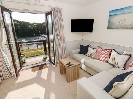 A living room with an open door leading to a waterfront view at Yacht Haven View in Neyland