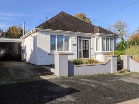 A single-story house with a black door two large windows and an attached garage at The Croft in Newport Pembrokeshire