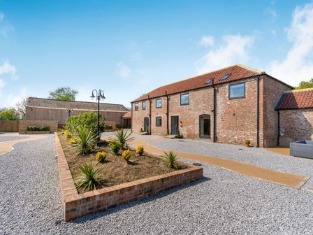 An outdoor area with a brick building a wooden shed gravel paths and a garden bed at Partridge Place in Burton Pidsea