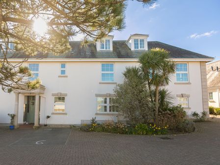 A two story house with dormer windows and an entrance with columns surrounded by plants and trees at Sand Dunes 6 The Manor in Lelant near Carbis Bay