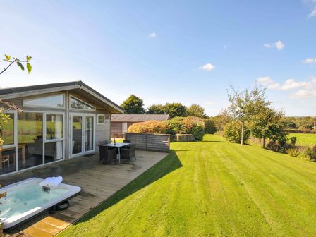 A garden with a deck, hot tub, table, and chairs at 3 Horizon View in Dobwalls