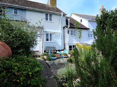 A garden with a blue table and two chairs outside a white house at 30 Sherborne Lane Lyme Regis