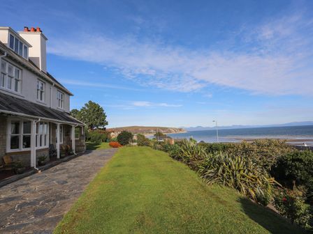 A house with a stone patio and garden overlooking the sea at 5 Craig Y Mor in Abersoch
