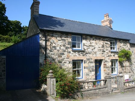 A stone house with blue doors and windows with a small garden at Delfryn Newport in Newport Pembrokeshire