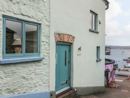 A light-colored exterior wall with blue door and windows near a harbor with boats at 1 The Old Brewhouse in Dartmouth