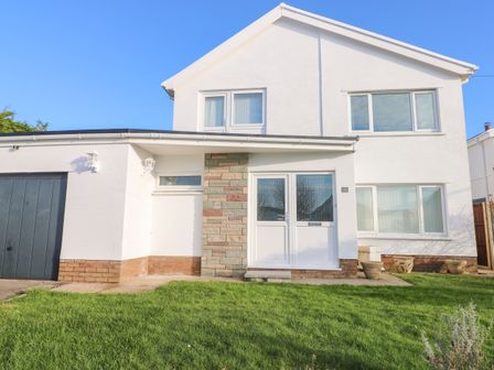 A two-story house with a garage and a green lawn at 30 Long Shepherds Drive in Newton near The Mumbles