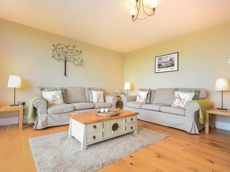 A living room with two sofas a coffee table lamps and wall art at The Pepper Pot in Warkworth