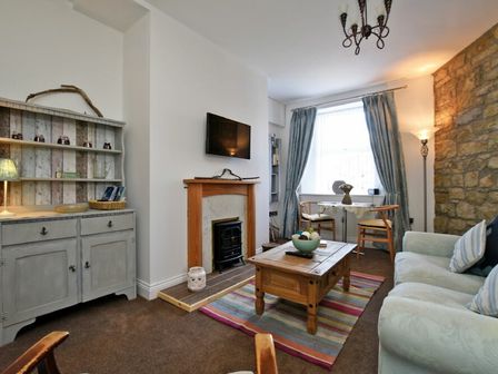 A living room with a sofa coffee table fireplace and cabinet at Sea Air in Amble