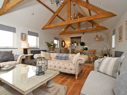 A living room with exposed wooden beams beige sofas a dining table and chairs at The Hemmel Beadnell