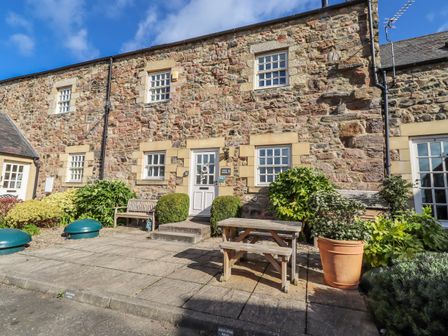 An outdoor area with a stone wall, door, and plants at No9 Budle Sands in Bamburgh