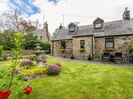A stone cottage with a garden and a multi-tiered stone fountain at Aryarch in Eglingham near Alnwick