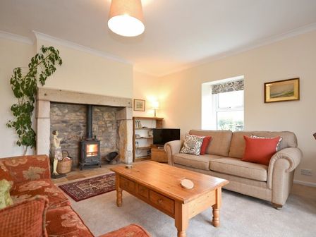 A living room with sofas a wooden coffee table a fireplace and a television at Dunrovin in Beadnell