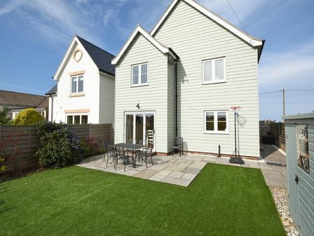 Back garden with patio table and chairs green lawn and basketball hoop at Portland in Beadnell