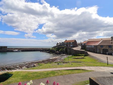 A view of a harbour with boats and houses at Coble Cottage in Craster