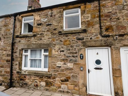 Stone exterior wall of a building with white framed windows and a white door numbered 4 at Percy Cottages No4 in Alnmouth