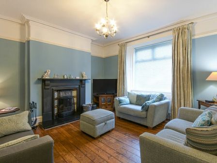 A living room with a fireplace two sofas an ottoman a wooden floor and a television at Nettie's View in Amble