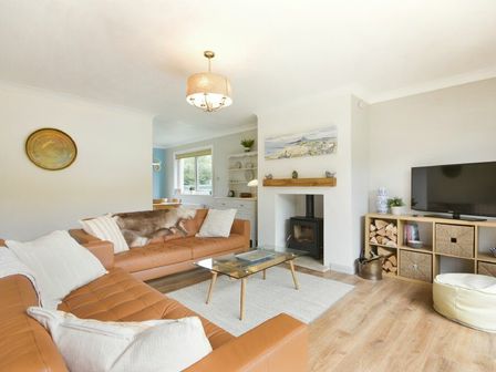 A living room with brown leather sofas a glass coffee table a wood-burning stove and a TV cabinet at Spuggies Rest in Embleton