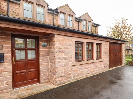 The exterior of a stone house with a wooden door and windows next to a wooden garage door at Stewart House Wooler