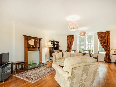 A living room with sofas a wooden fireplace a television dining table and chairs at The Old Concert Room in Alnmouth