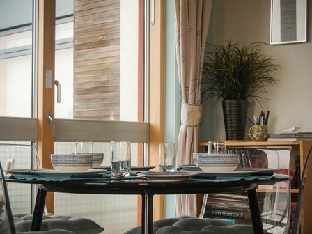 A dining table set with bowls and glasses by a window with wooden frame and curtains at Castle View at the Viking in Seahouses