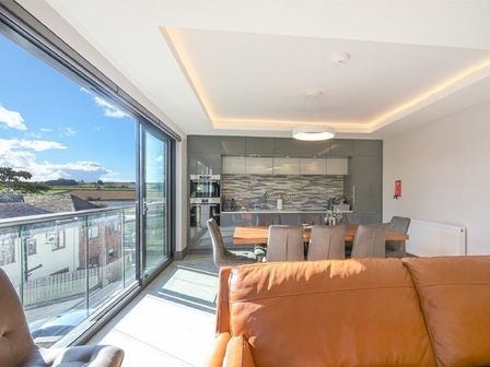 A kitchen and dining area with a large glass window overlooking buildings and fields at Riverview Alnmouth