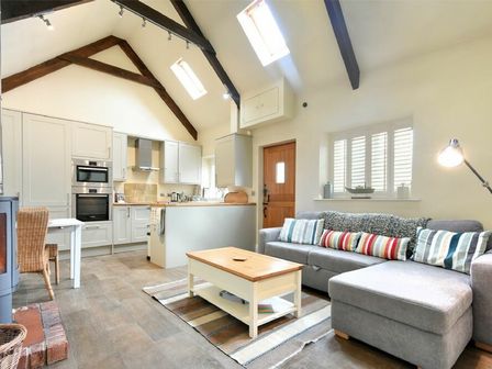 A living room and kitchen with a gray sofa and coffee table at Martins Cottage in Alnmouth