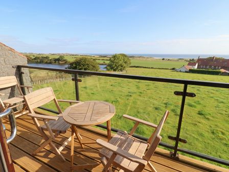A balcony with a table and chairs overlooking the ocean at Links View in Embleton