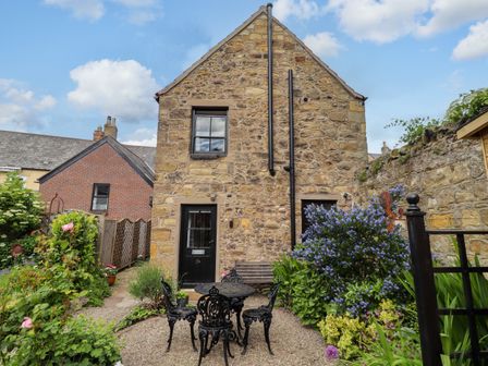 A stone building with a garden and seating area at Lavender Cottage (Bailiffgate) Alnwick