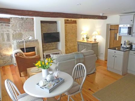 A living area with a round table and chairs a sofa an armchair and kitchen cabinets at Dorothy Forster Court in Alnwick