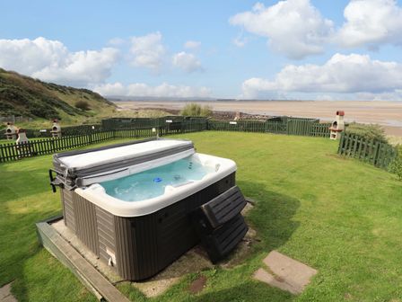 A hot tub in a grassy area with a fence at Heather Cottages - Grey Seal in Bamburgh