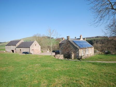 A rural scene with stone buildings and solar panels on one in Kirknowe Jedburgh