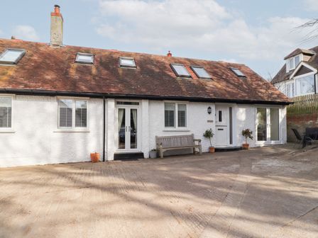 A white cottage with skylights and a bench in front at Old Stable Cottage Alnmouth