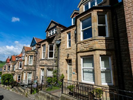 A row of stone houses with bay windows and small front gardens at Upper Alnbank in Alnmouth