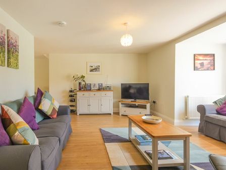 A living room with sofas and a coffee table with books and a bowl at Schooner Court No2 in Alnmouth