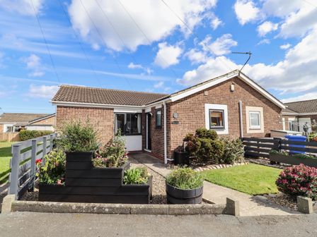 A house with a garden and flower bed at Flora Cottage Beadnell